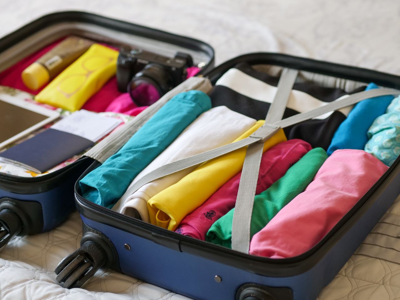 Services Open suitcase neatly packed with colorful clothes and travel essentials.
